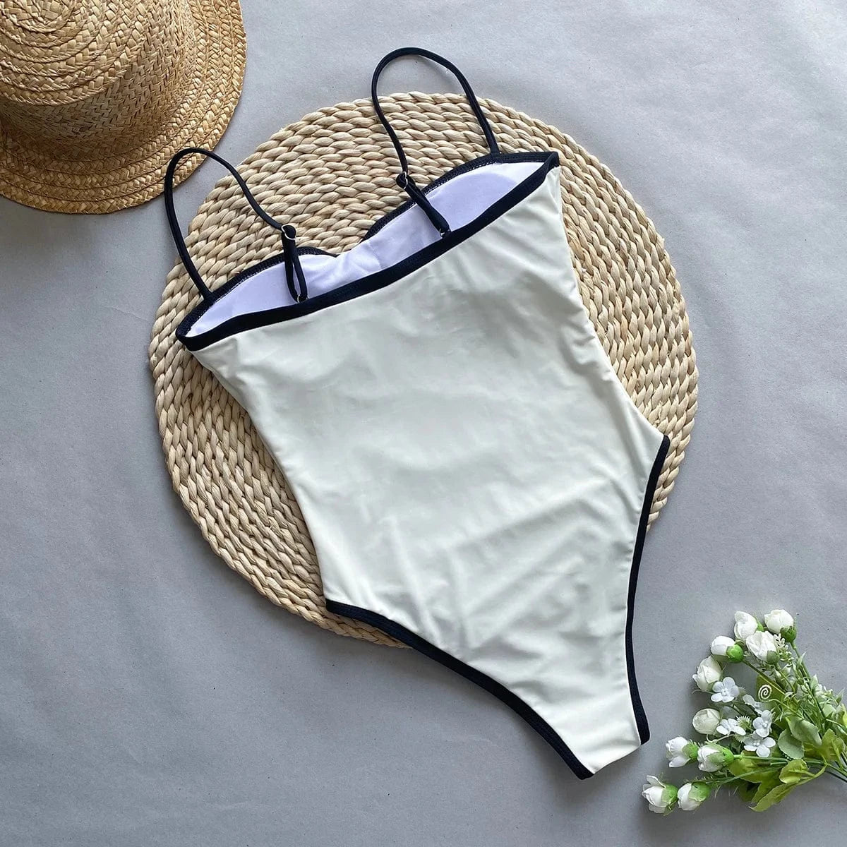 Maillot de bain une pièce blanc échancré, détails noirs, idéal pour l'été et allure élégante.