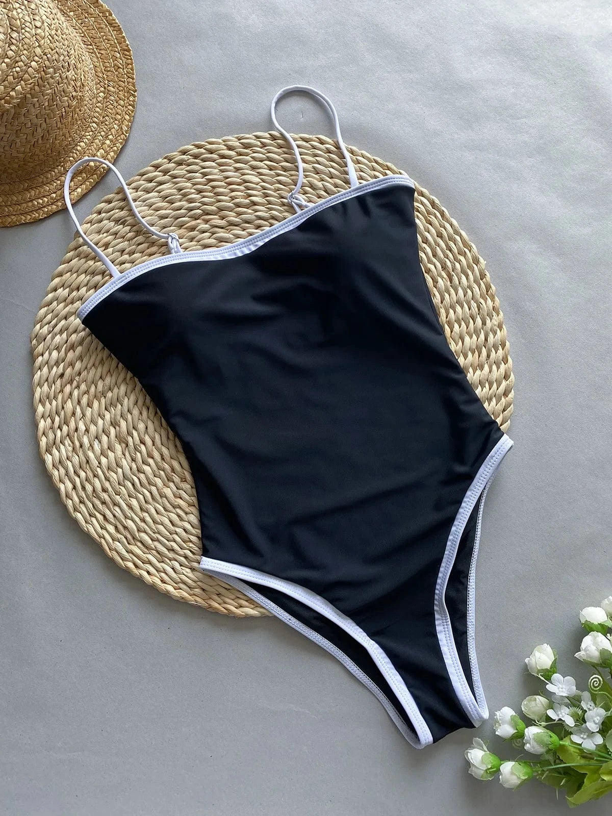 Maillot de bain 1 pièce noir échancré avec bretelles fines, idéal pour l'été à la plage.