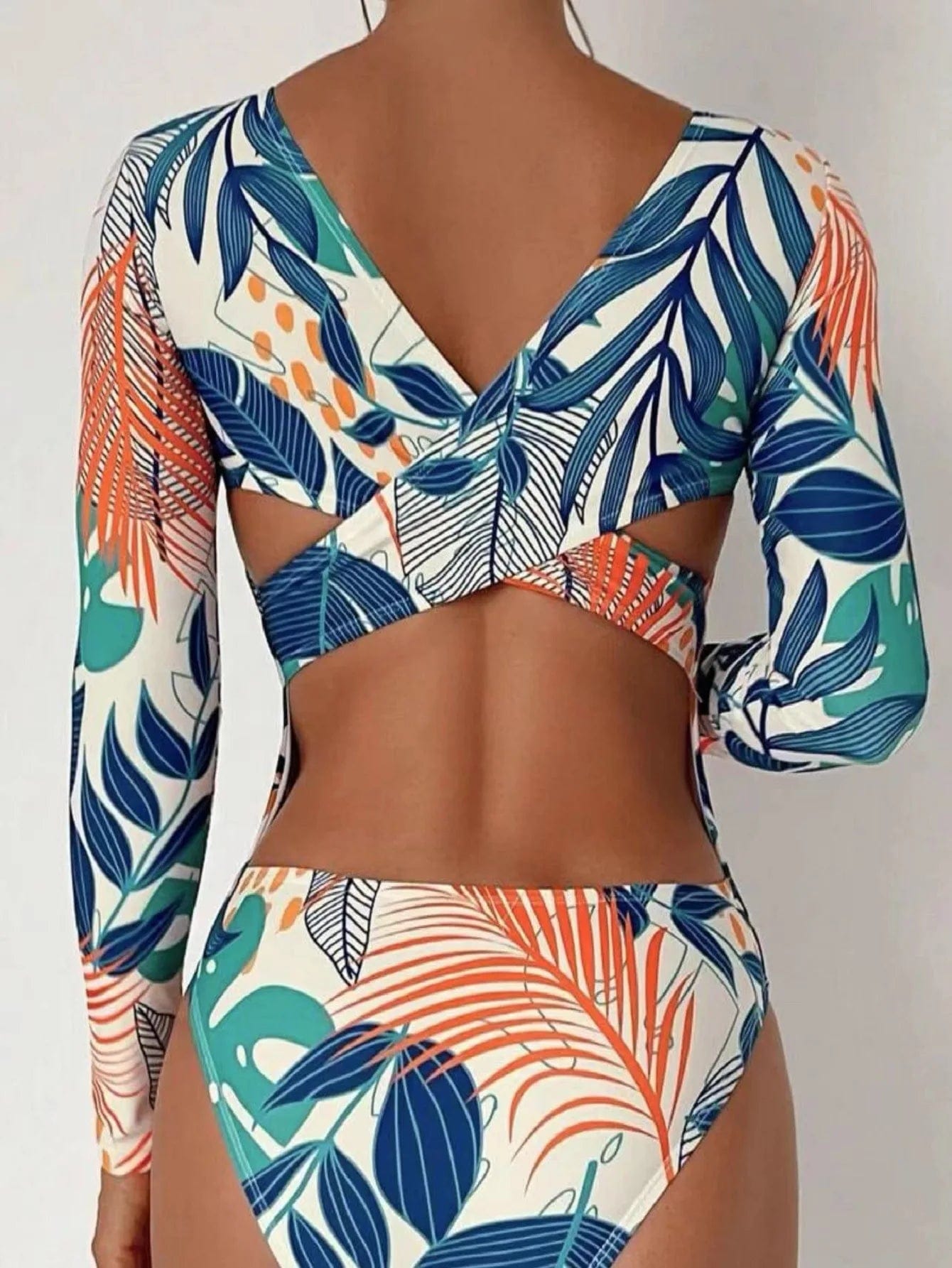Maillot de bain femme une pièce à manches longues avec imprimé tropical coloré et dos croisé.