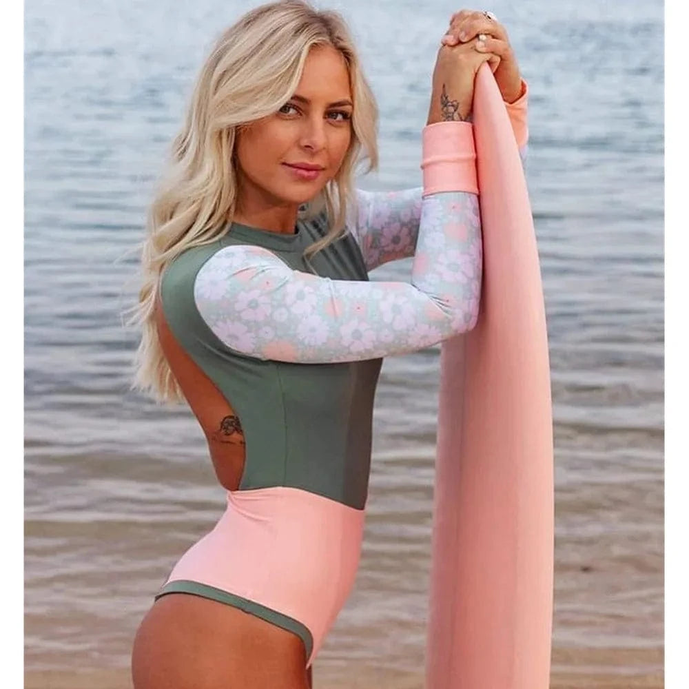 Maillot de bain une pièce femme imprimé floral pastel, manches longues, au bord de la mer.