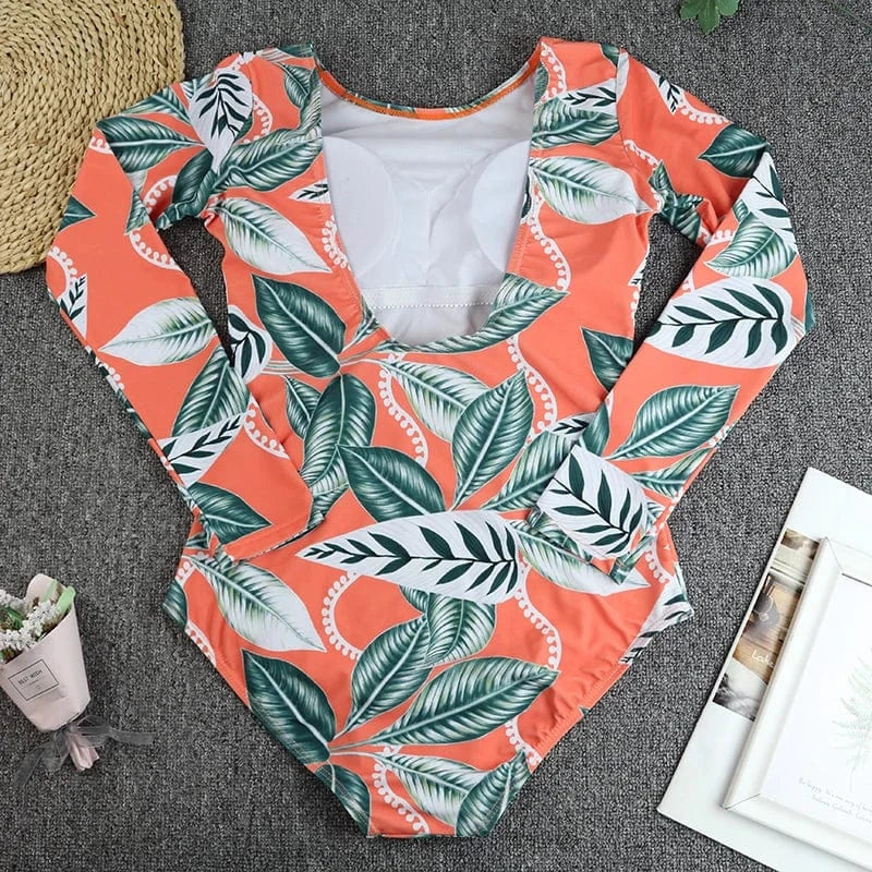Maillot de bain femme une pièce manches longues, imprimé feuilles tropicales sur fond orange.