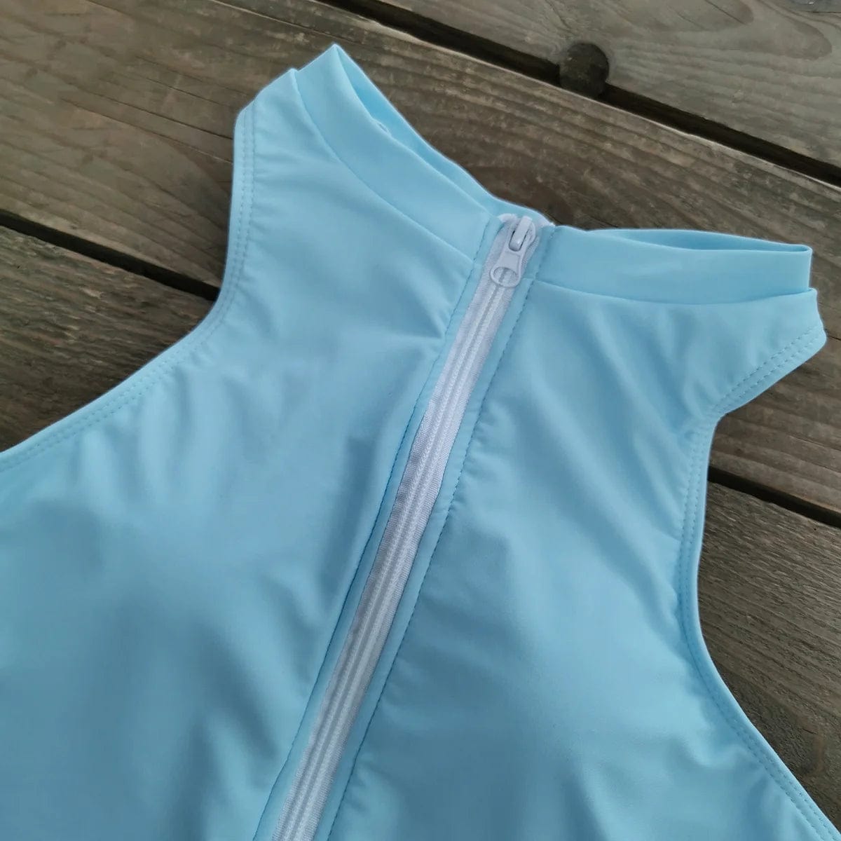 Maillot de bain une pièce bleu clair avec fermeture éclair, dos élégant et moderne pour femme.