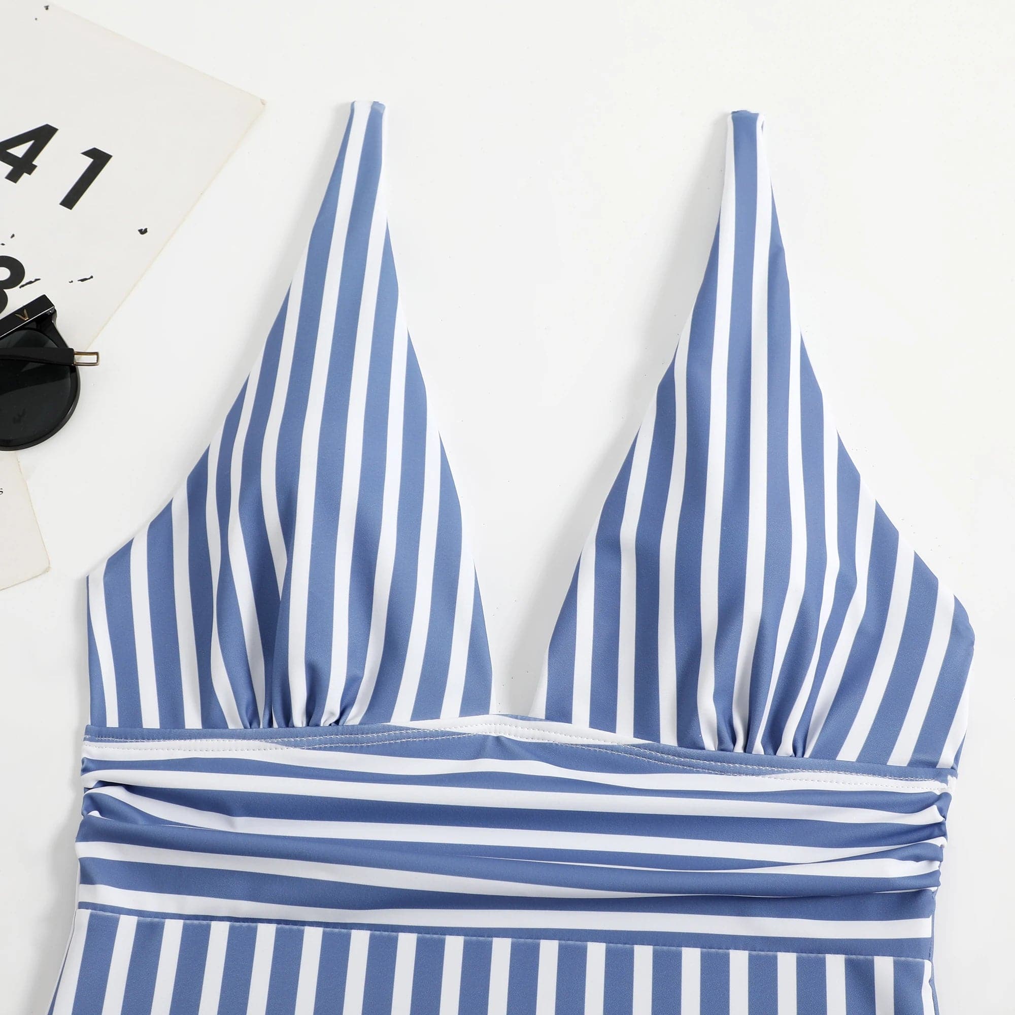 Maillot de bain une pièce pour femme à rayures bleues et blanches, style élégant et moderne.