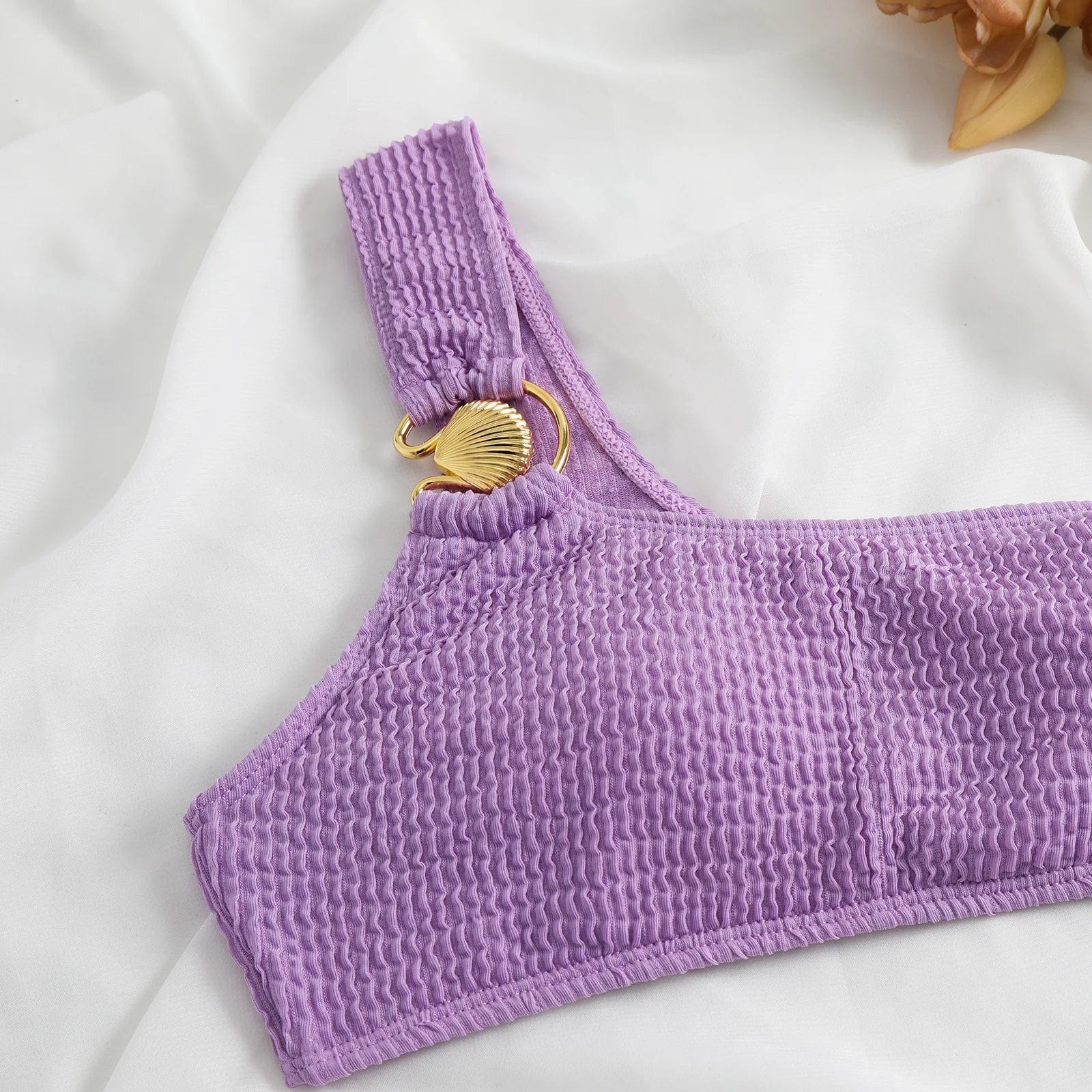 Maillot de bain femme asymétrique violet, texture gaufrée, au design élégant avec ornement doré.