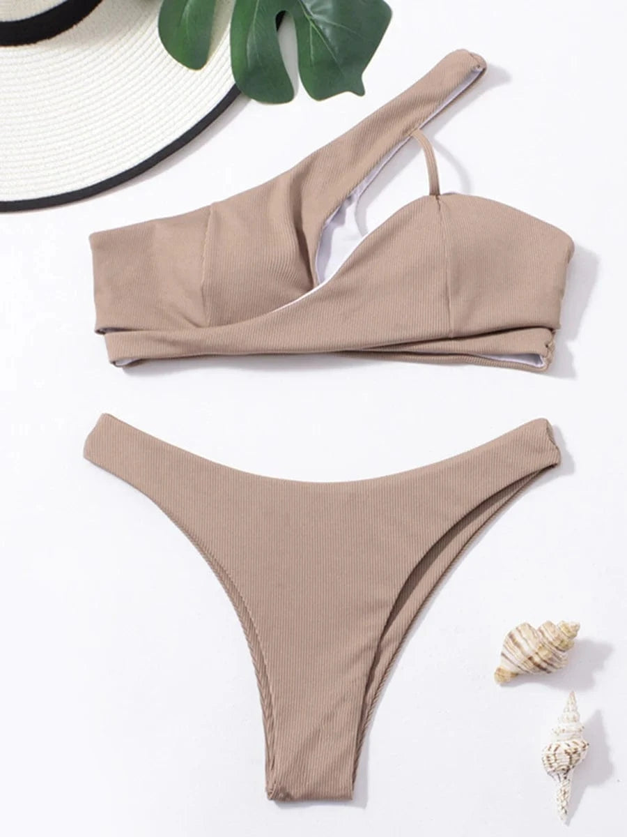 Maillot de bain femme asymétrique beige avec accessoires plage élégants pour l'été.