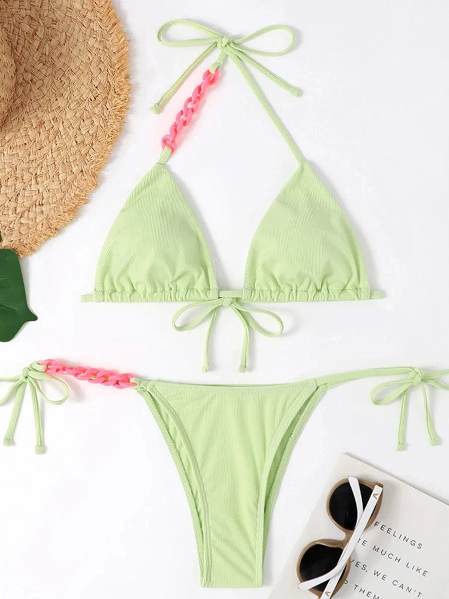 Maillot de bain femme triangle vert clair avec détails crochetés roses et liens ajustables.