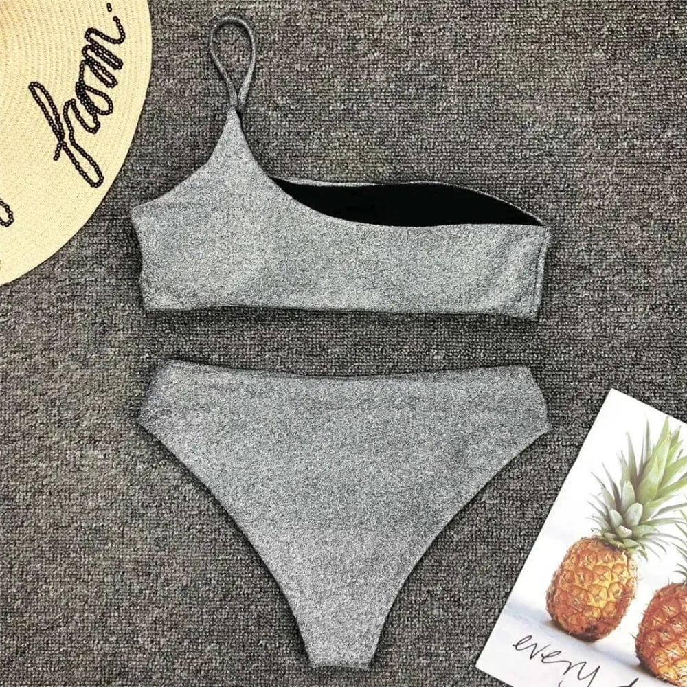 Maillot de bain femme asymétrique couleur argentée avec effet pailleté, tendance plage.