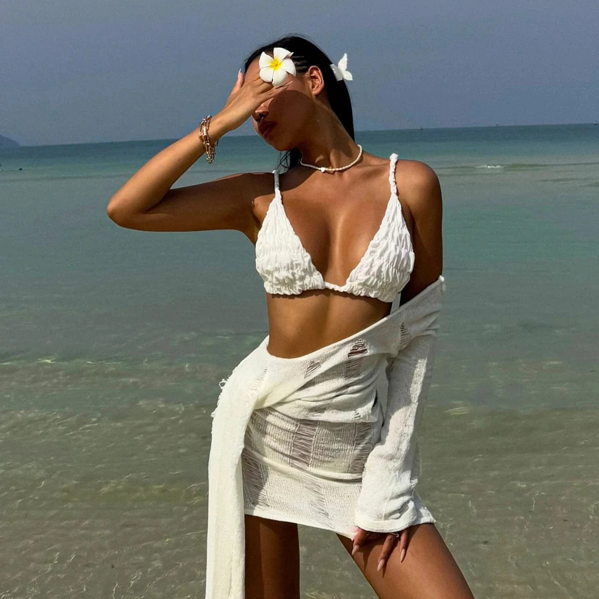 Maillot de bain blanc sexy pour femme avec détails élégants sur une plage exotique ensoleillée.