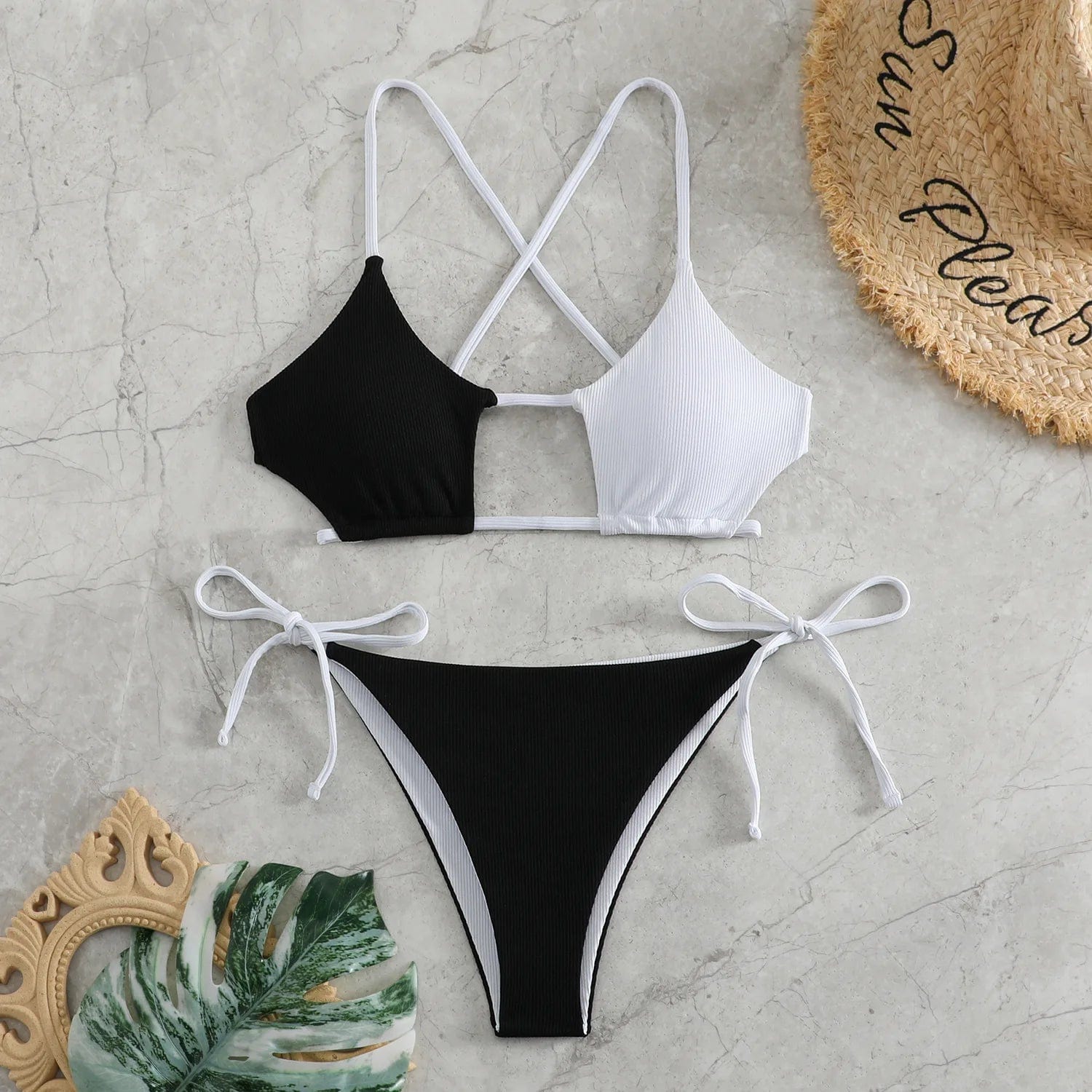 Maillot de bain bikini femme en patchwork noir et blanc sur fond de marbre avec accessoire d'été.