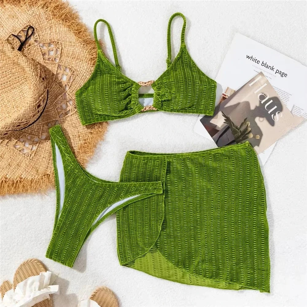 Maillot de bain femme en trois pièces vert réparti sur une serviette, avec chapeau d'été et magazines.