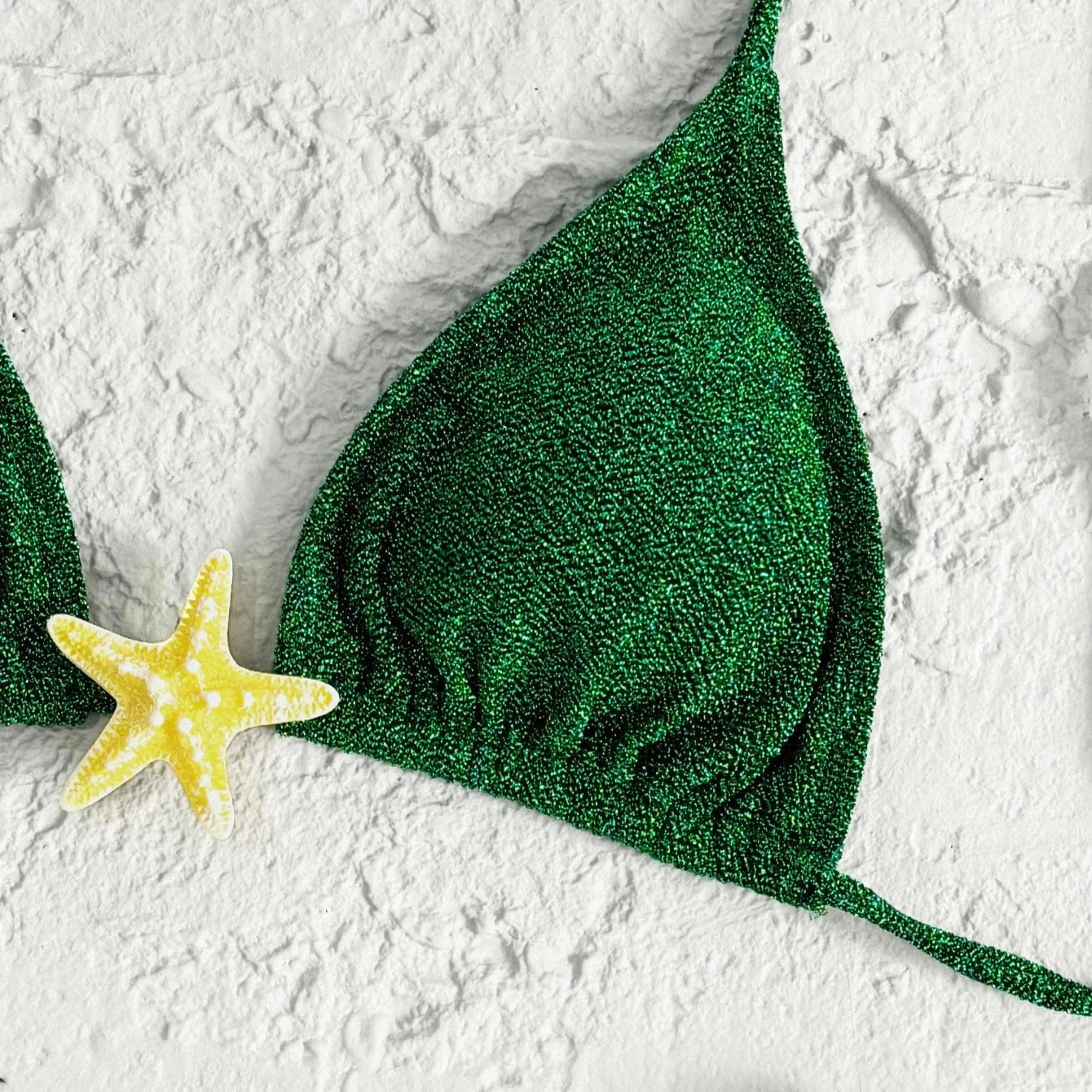Maillot de bain bikini femme vert émeraude pailleté avec motif étoile de mer jaune sur sable.