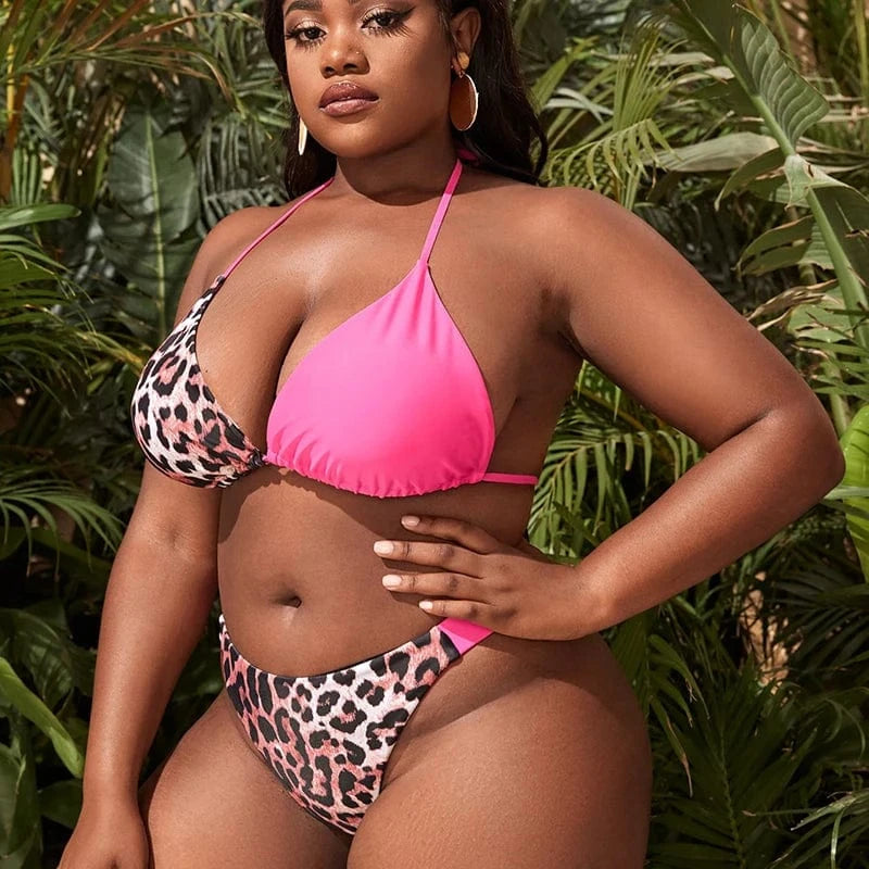 Maillot de bain grande taille léopard et rose pour femme devant des feuilles tropicales.