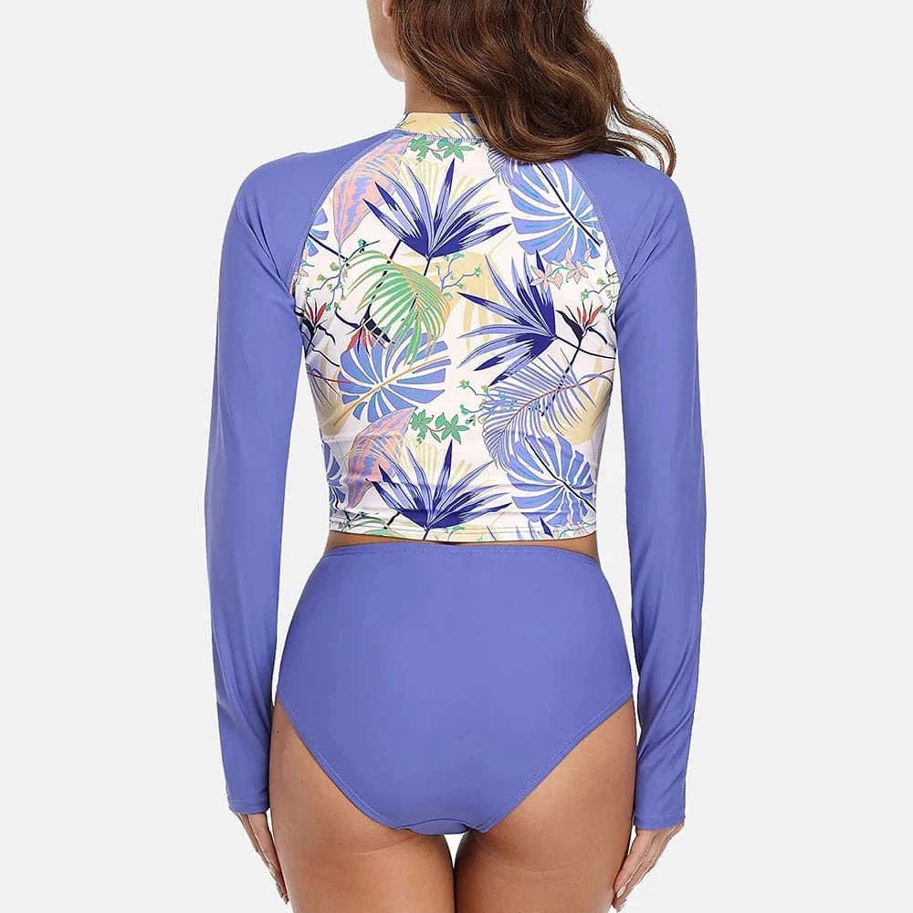 Maillot de bain femme manches longues, motif floral tropical, fond bleu élégant et chic.