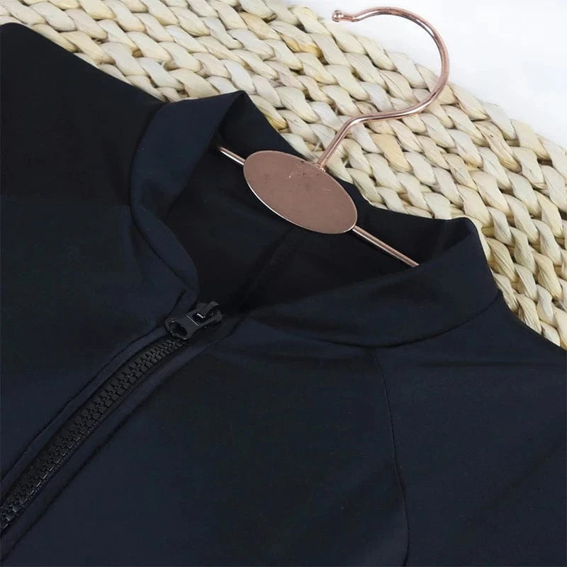Maillot de bain femme noir élégant avec manches longues et fermeture éclair pour style chic et sport.