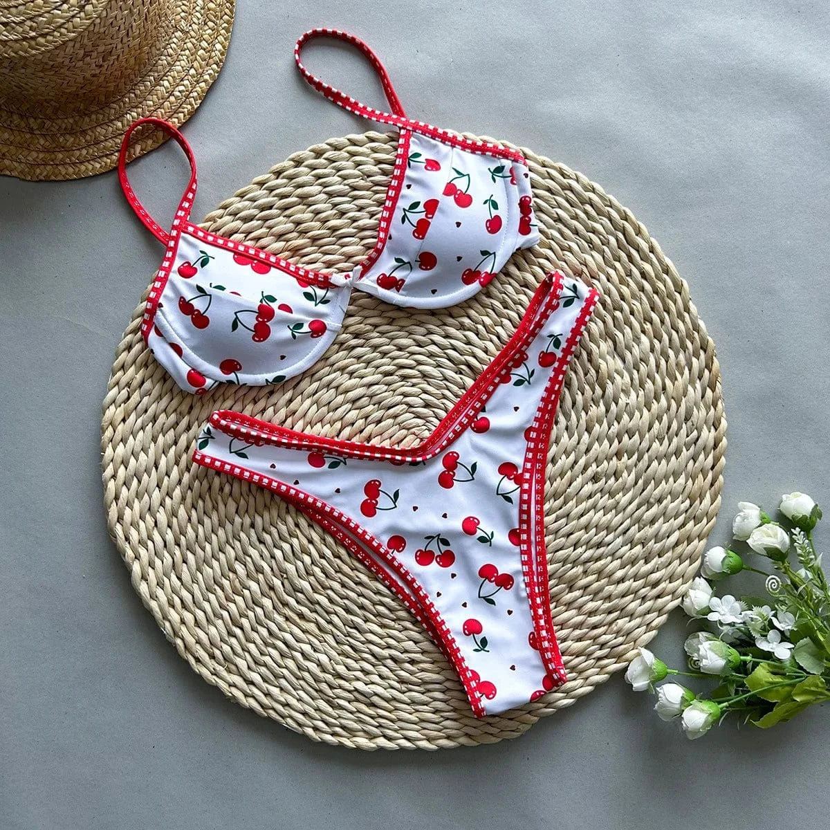 Maillot de bain femme à motif cerises rouges sur fond blanc, avec bordures rouges élégantes.