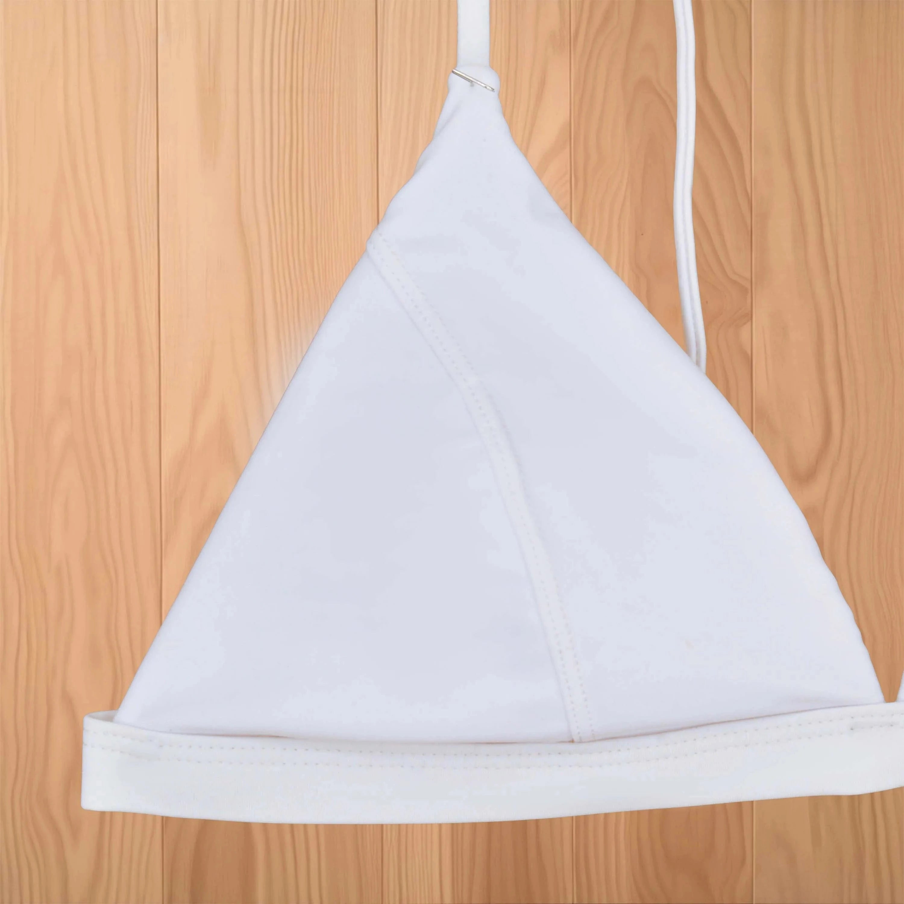 Maillot de bain femme triangle blanc élégant, parfait pour l'été, sur fond de bois naturel.