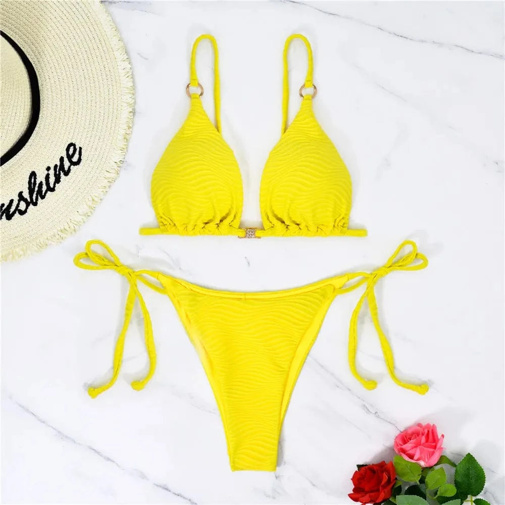 Maillot de bain femme triangle échancré jaune vif sur fond marbré avec chapeau et fleurs.
