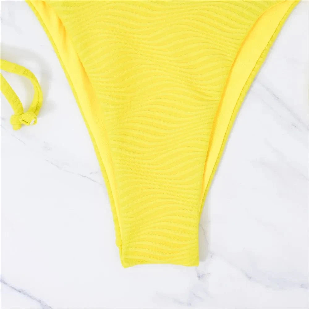 Maillot de bain femme triangle en jaune vibrant, échancré, avec motif ondulé élégant sur tissu.