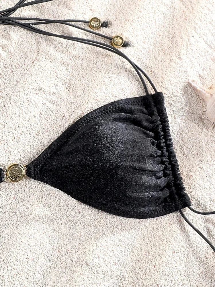 Maillot de bain noir triangle ficelle pour femme, élégant et raffiné sur fond de sable.