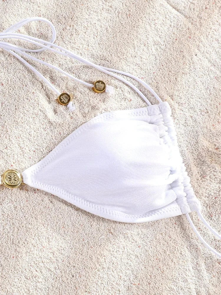 Maillot de bain femme triangle ficelle blanc élégant posé sur du sable pour un style estival.