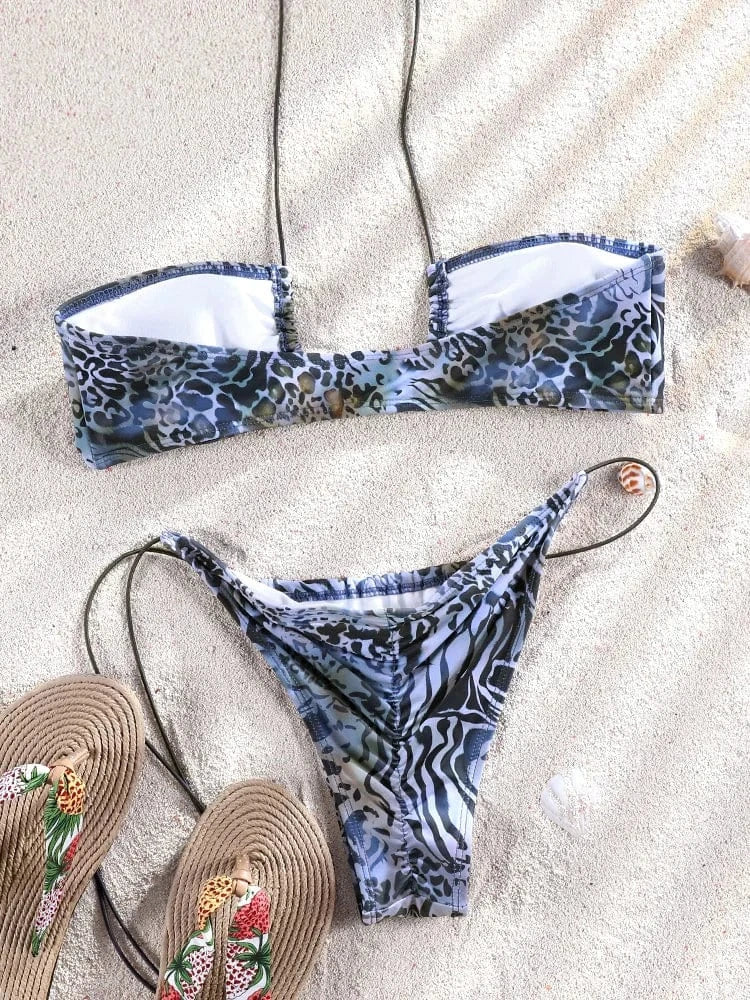 Maillot de bain femme imprimé animal triangle avec ficelles, posé sur le sable avec des tongs.