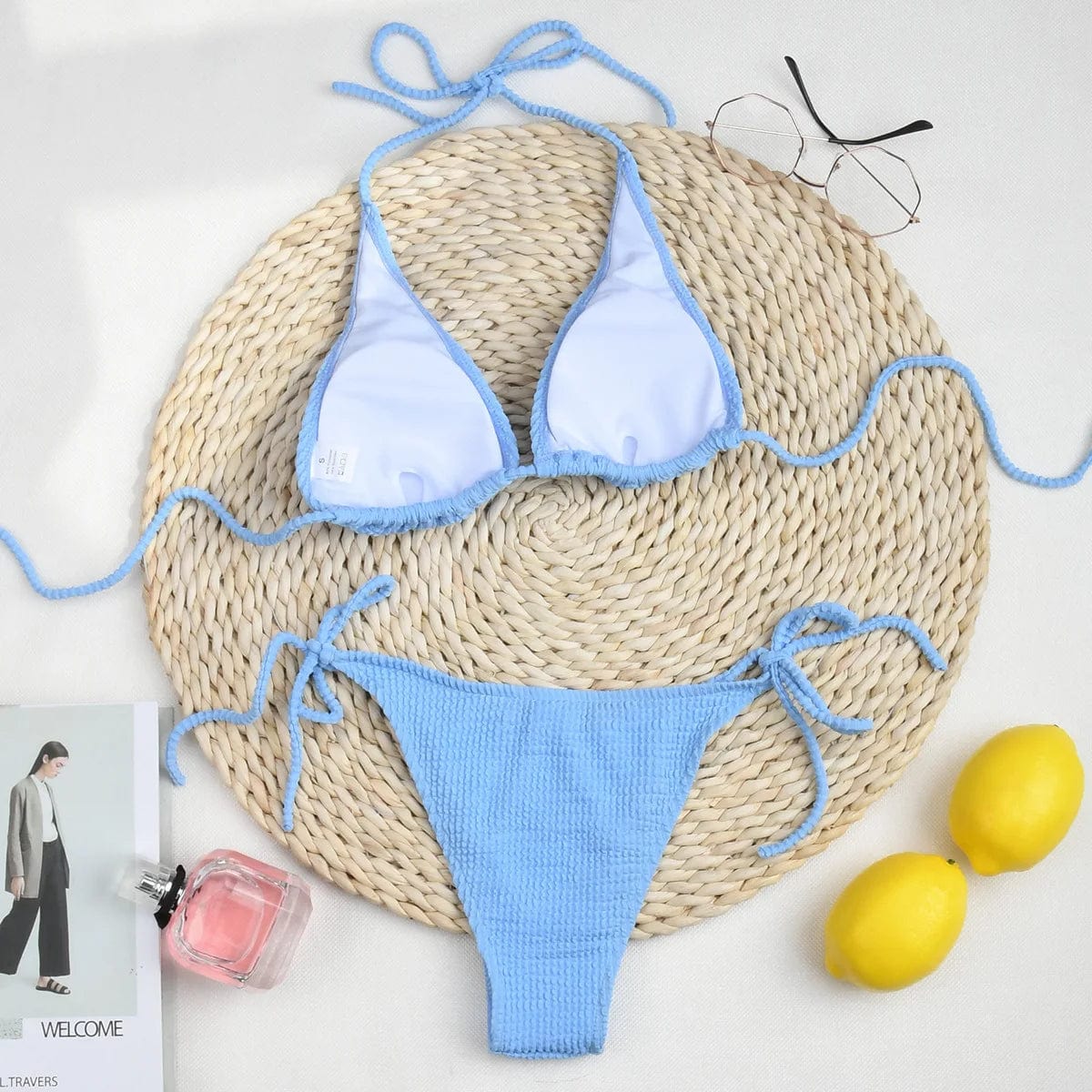 Maillot de bain triangle bleu clair pour femme, style estival posé sur un tapis circulaire.