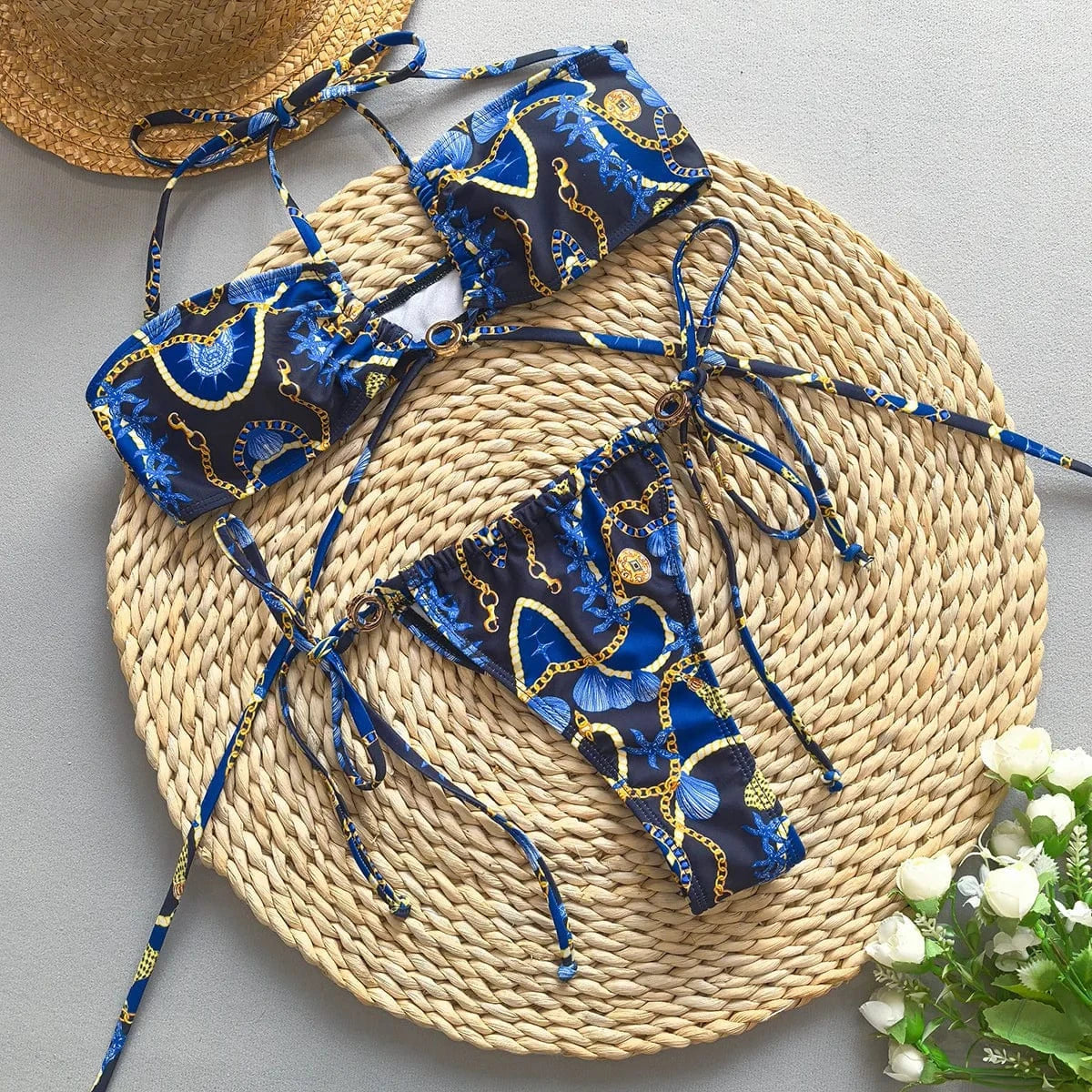 Maillot de bain femme deux pièces bleu à motifs dorés, style chic pour l'été, avec détails coquillages.