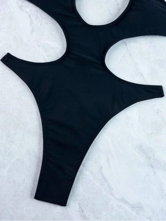 Maillot de bain une pièce noir femme, style échancré pour un look élégant et moderne sur la plage.