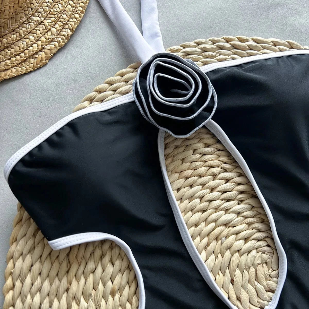 Maillot de bain une pièce noir élégant avec détail fleur, idéal pour un look estival chic.